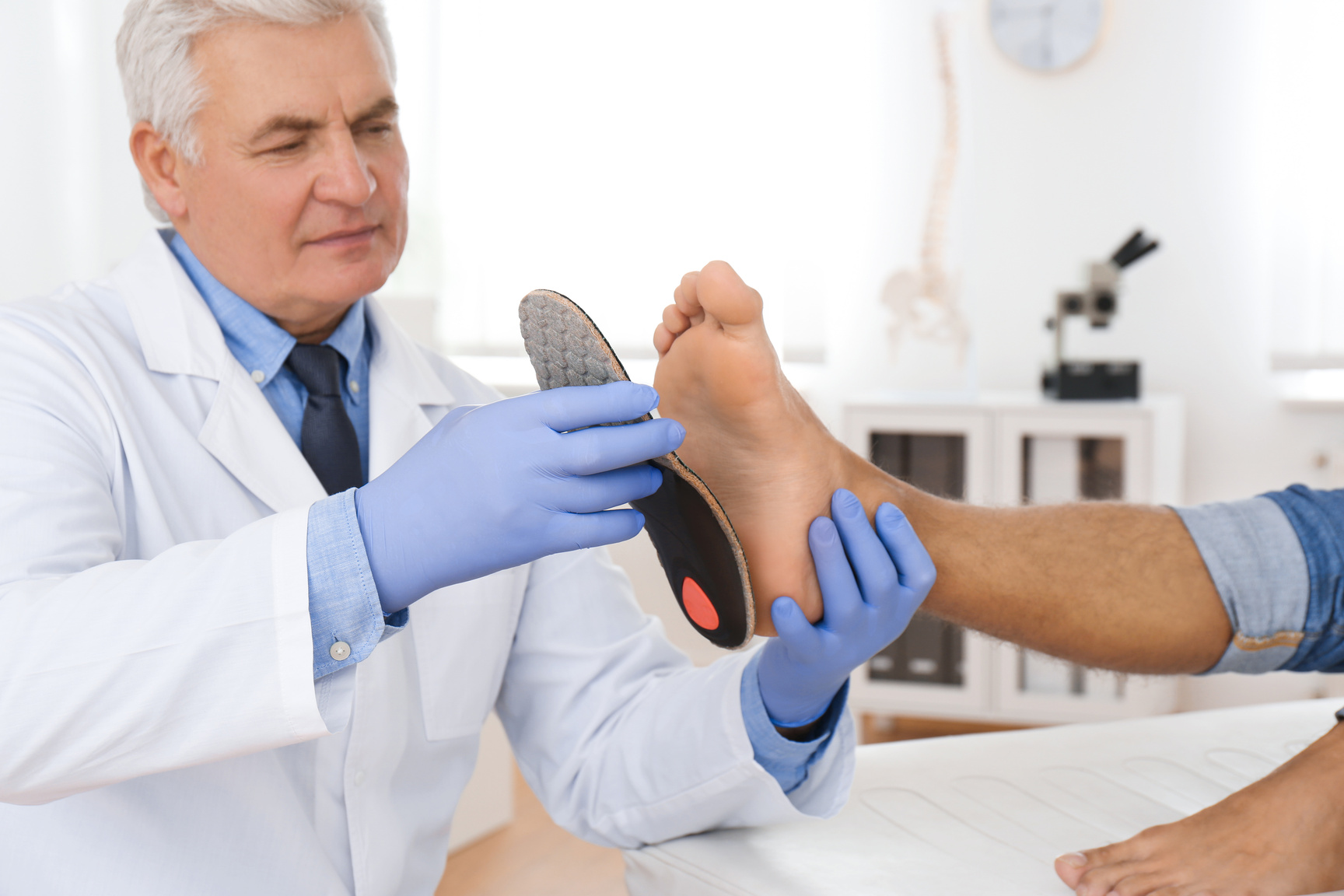 Male Orthopedist Fitting Insole on Patient's Foot in Clinic