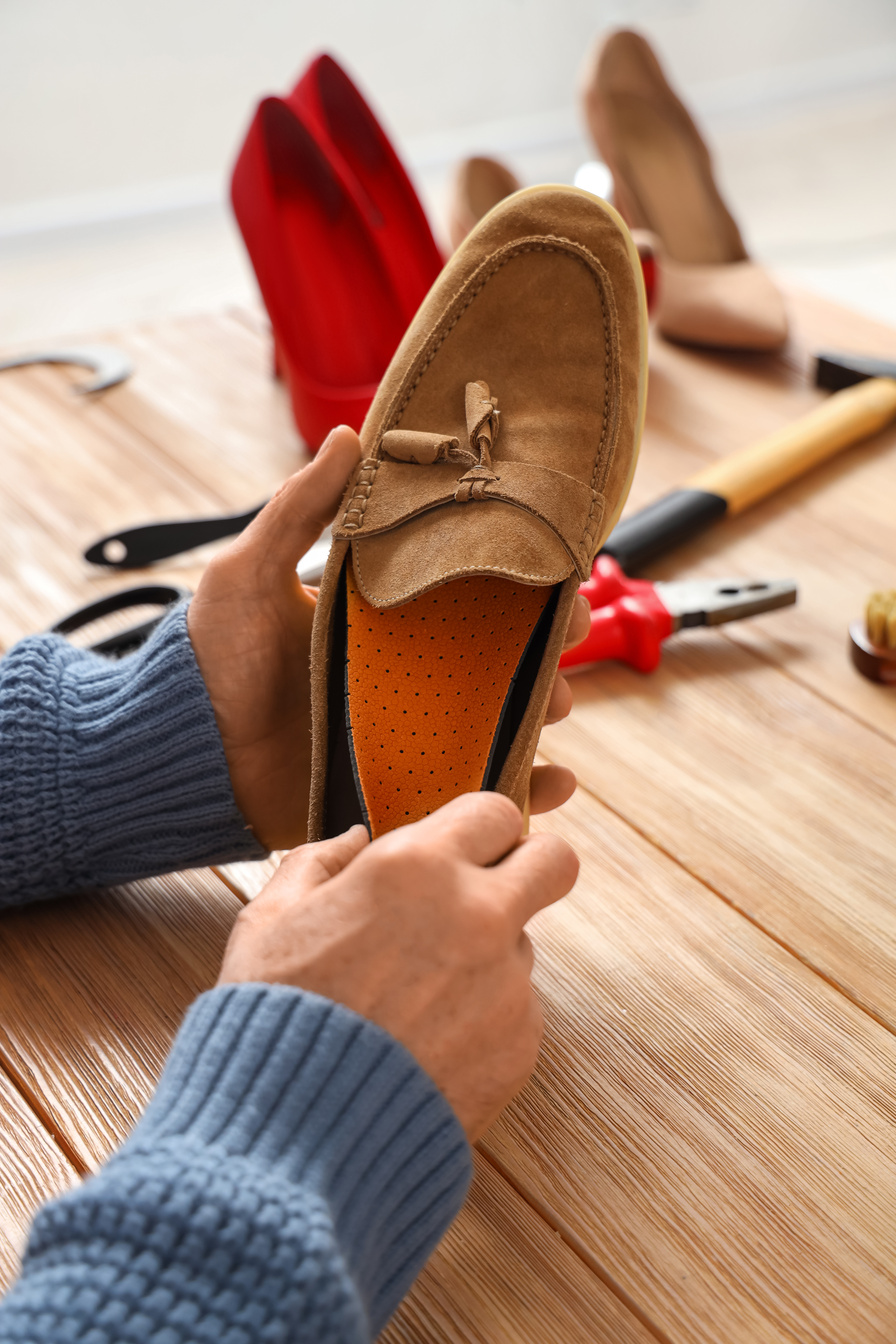 Mature Shoemaker Putting Insole into Shoe at Table in Workshop, Closeup